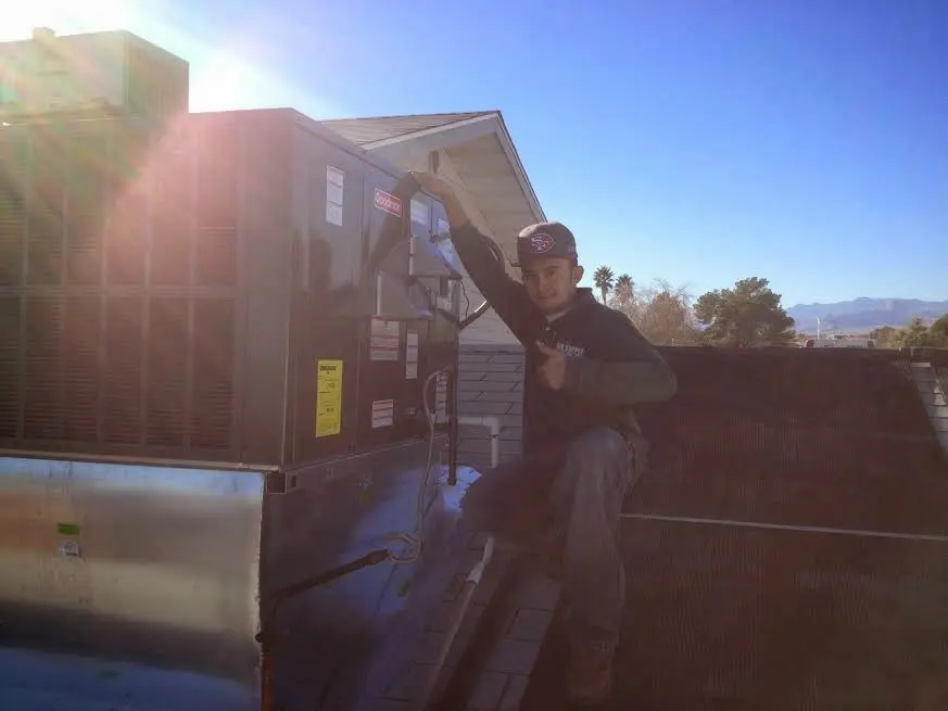 HVAC technician performing Heat Pump Repair on a rooftop unit in Farmington